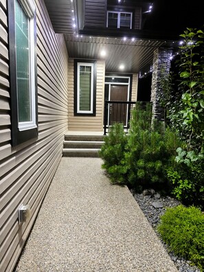 A house with a gravel pathway leading to the front door, surrounded by greenery and a stone wall. - Elegant and Spacious Getaway in St. Albert. 4 BR's, AC and Premium Amenities. (St. Albert)