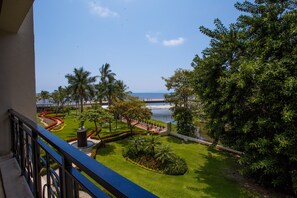 A balcony with a view of a landscaped garden, palm trees, and a body of water. - Molino De Agua 209 Located in Old Town on Los Muertos Beach 3BD Condo for rent i (Puerto Vallarta)