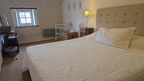 Un dormitorio con una cama grande, una mesita de noche con lámpara, una ventana y un radiador.
