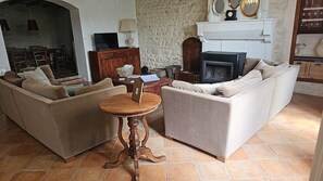 Una sala de estar con dos sofás, una mesita redonda, una chimenea y una pared de piedra.