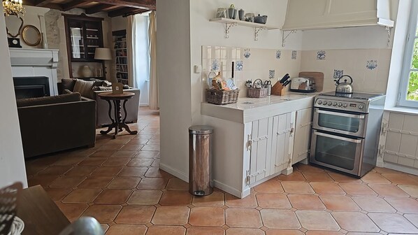 Una cocina con una isla central, estufa, horno y comedor con sofá y mesa.