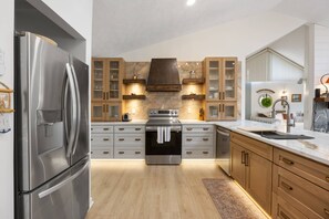 Une cuisine moderne dotée d’appareils électroménagers en acier inoxydable, de meubles en bois et d’un dosseret en marbre.