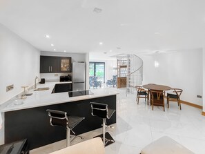 A modern kitchen with a central island, black bar stools, and a dining area with a wooden table and chairs. - Coach House - UK52274 (Helmsley)