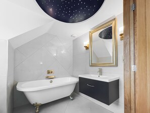 A bathroom with a freestanding bathtub, a vanity with a mirror, and a ceiling light fixture. - Coach House - UK52274 (Helmsley)