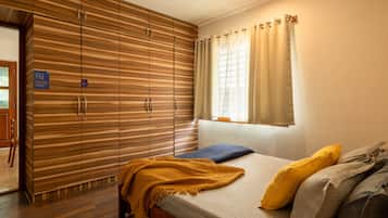 Un dormitorio con una cama, un armario de madera, una ventana con cortinas y una puerta con un cartel.