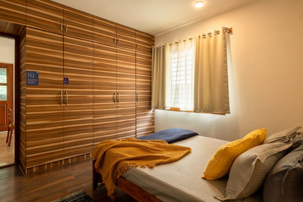 Un dormitorio con una cama, un armario de madera, una ventana con cortinas y una puerta con un cartel.