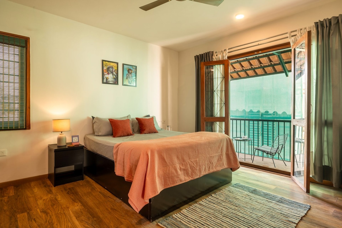 A bedroom with a bed, bedside table, lamp, and artwork on the wall.