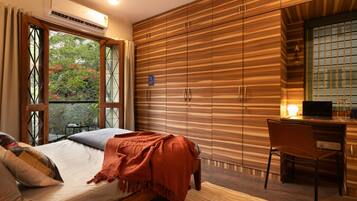 Un dormitorio con cama, escritorio y vista a zonas verdes.