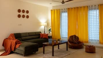 Una sala de estar con un sofá, una mesa de centro, una silla y un ventilador de techo.