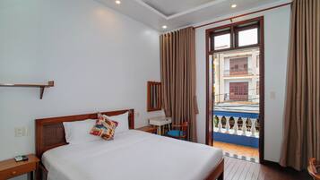 Une chambre d’hôtel avec un lit, une table de chevet, une chaise et une vue sur l’extérieur.