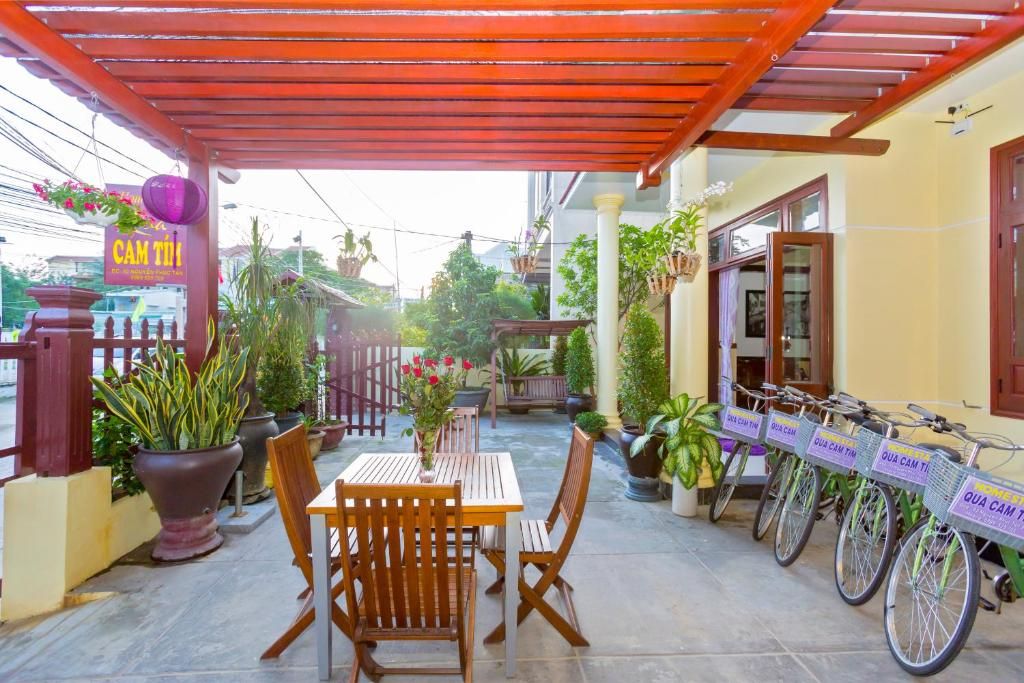 Un patio couvert avec une table et des chaises, des plantes en pot et des vélos.