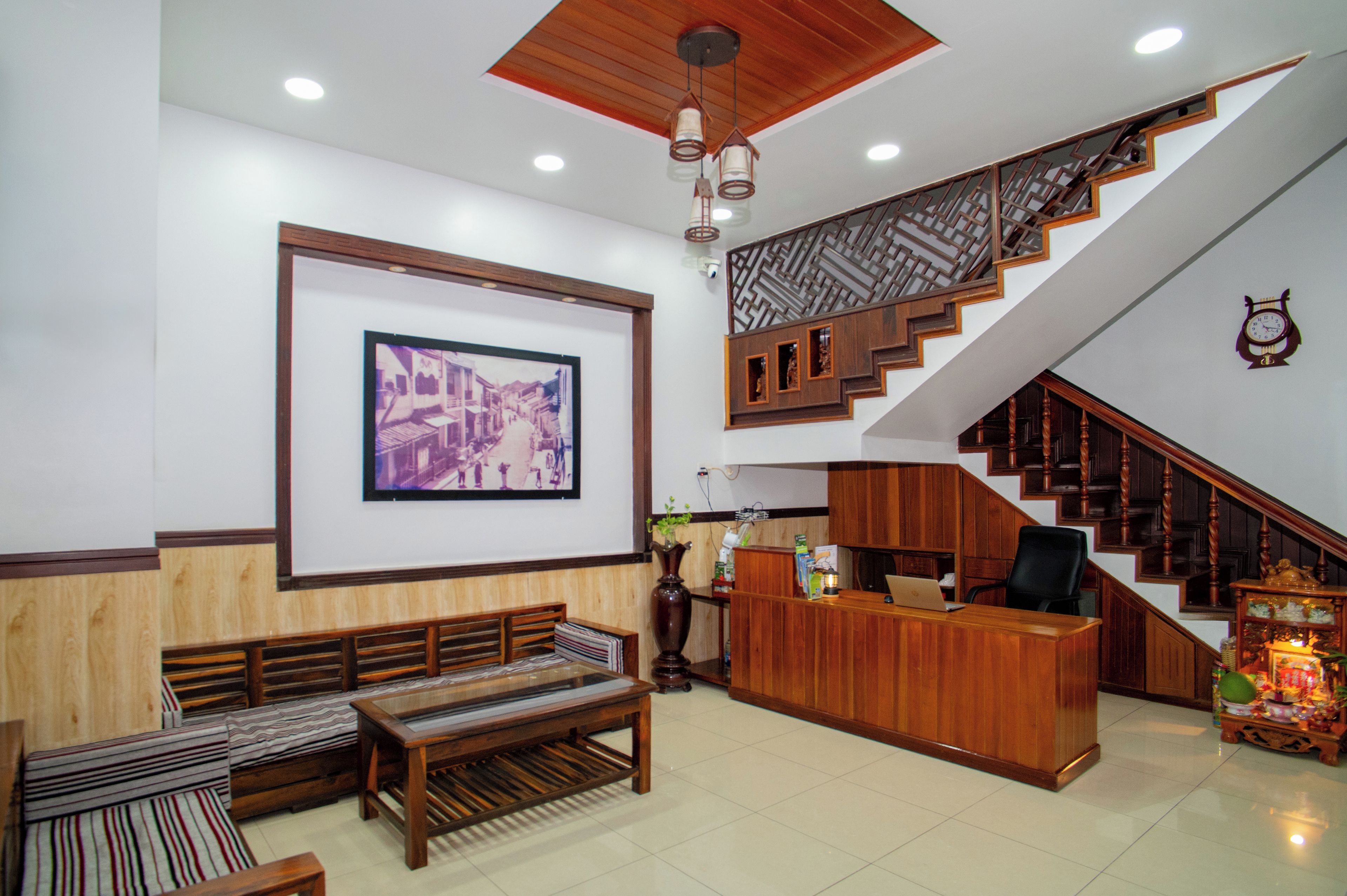 A reception area with a wooden desk, a bench, and a staircase with a patterned railing.
