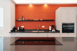 Eine moderne Küche mit schwarzem Arbeitsplatz, einer Edelstahl-Spüle und einem eingebauten Backofen.