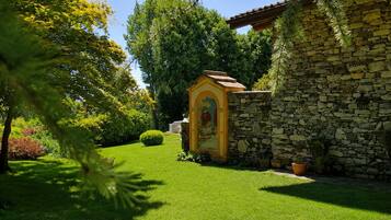 Un edificio in pietra con un piccolo ingresso ad arco, circondato da erba curata e alberi.