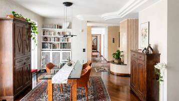 Un soggiorno spazioso con zona pranzo, pavimento in legno e libreria.
