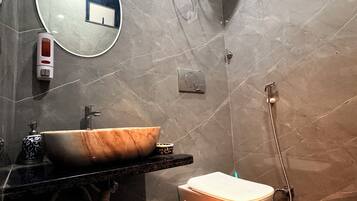 Ein modernes Badezimmer mit Marmorwaschbecken, einem runden Spiegel, einer Toilette und einer Duschkabine.