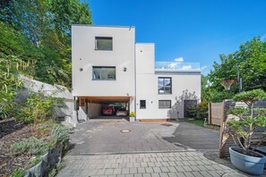 A modern two-story building with a covered driveway and a basketball hoop. - 25 Min to Munich Luxury 370 m² 4,000 sqft Villa Aircon + Heat Pump (Eching)