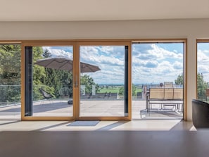 A modern interior with large sliding glass doors leading to an outdoor patio area. - 25 Min to Munich Luxury 370 m² 4,000 sqft Villa Aircon + Heat Pump (Eching)