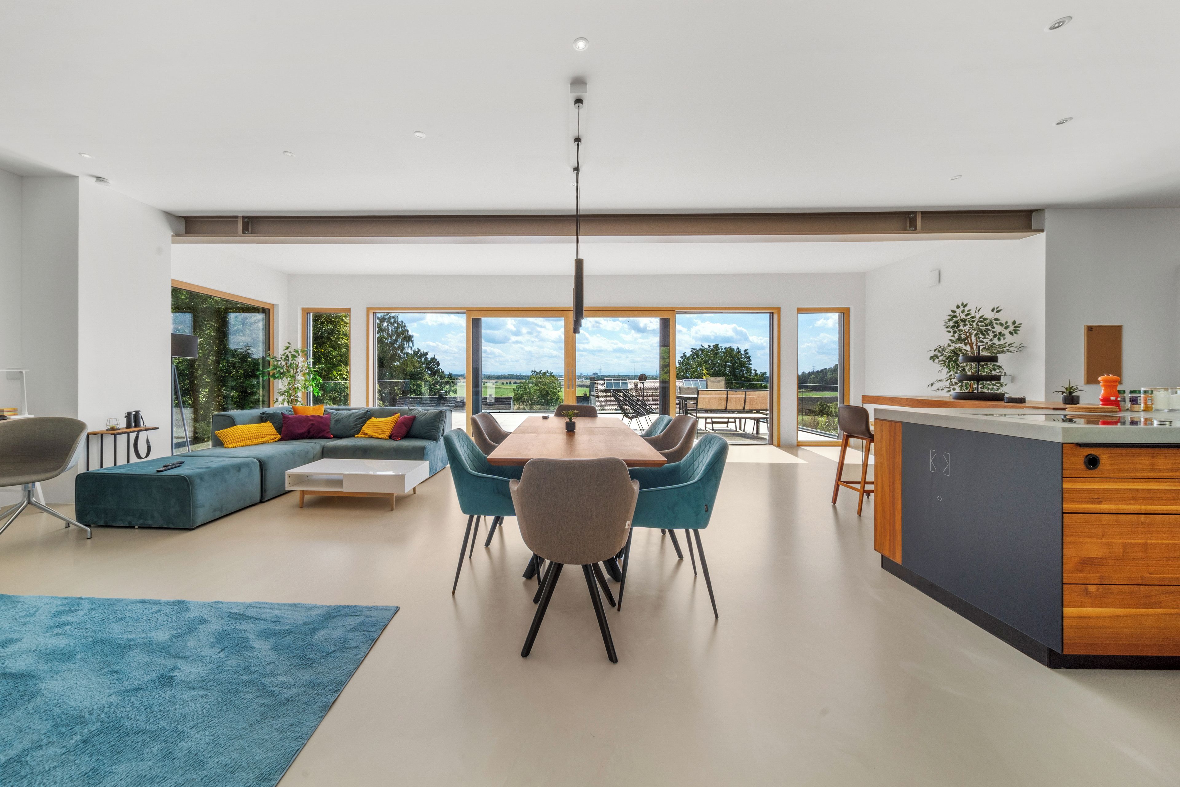 A modern living space with a dining area, kitchen, and large windows offering a view of the outdoors.