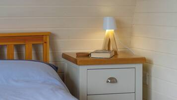 Une table de chevet avec une lampe, un livre et un tiroir.