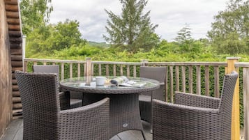 A wooden deck with wicker furniture and a glass table.