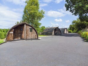 Une rangée de cabanes en bois rustiques, avec une allée pavée menant à elles.