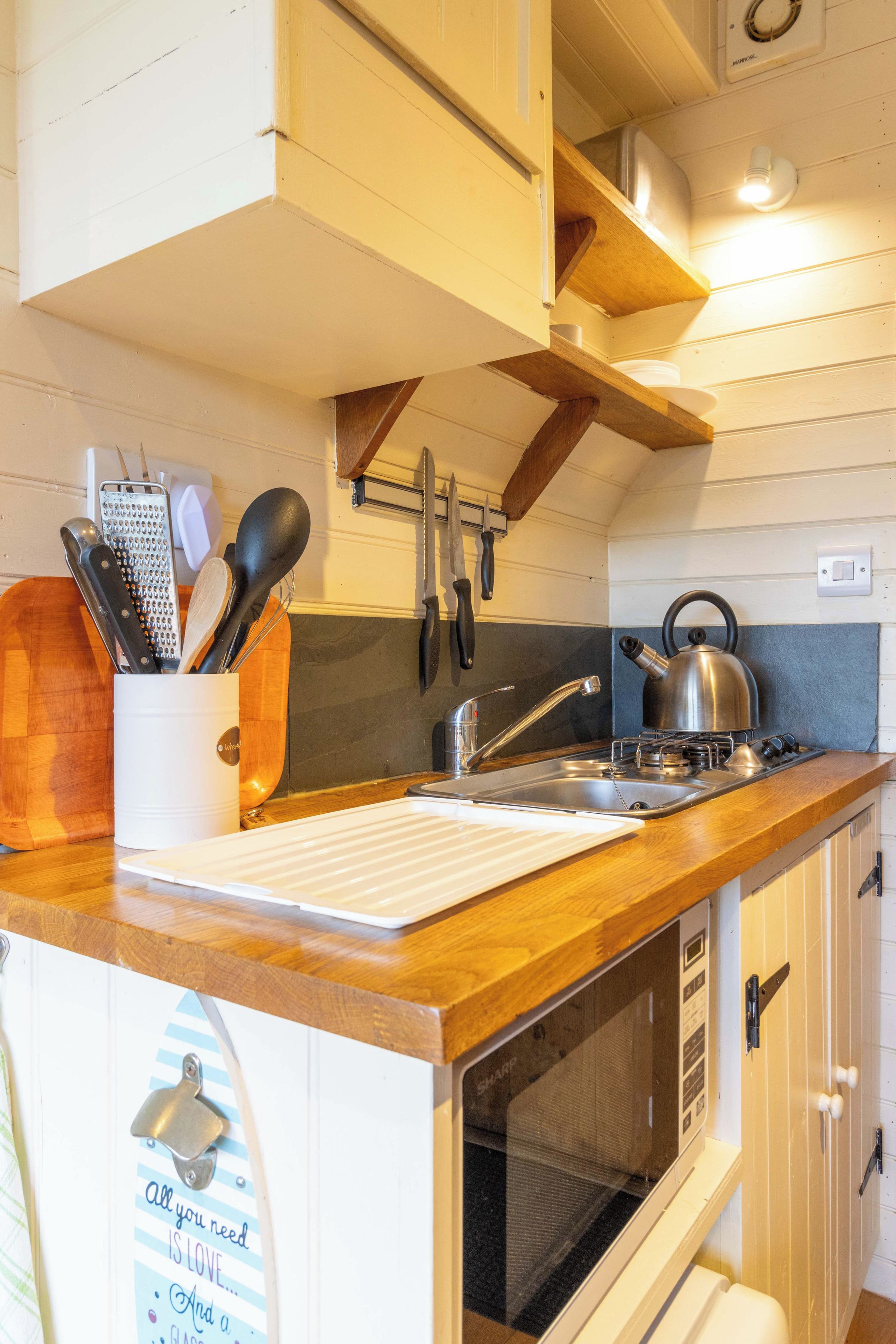 A compact kitchen with a wooden countertop, a built-in oven, and a sink.