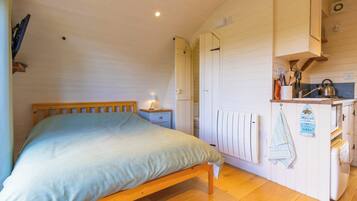 Une chambre à coucher avec un lit en bois, une table de chevet avec une lampe et un radiateur blanc.