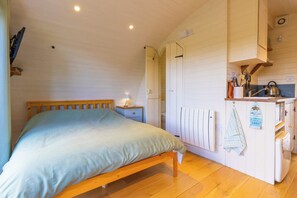 Une chambre à coucher avec un lit en bois, une table de chevet avec une lampe et un radiateur blanc.
