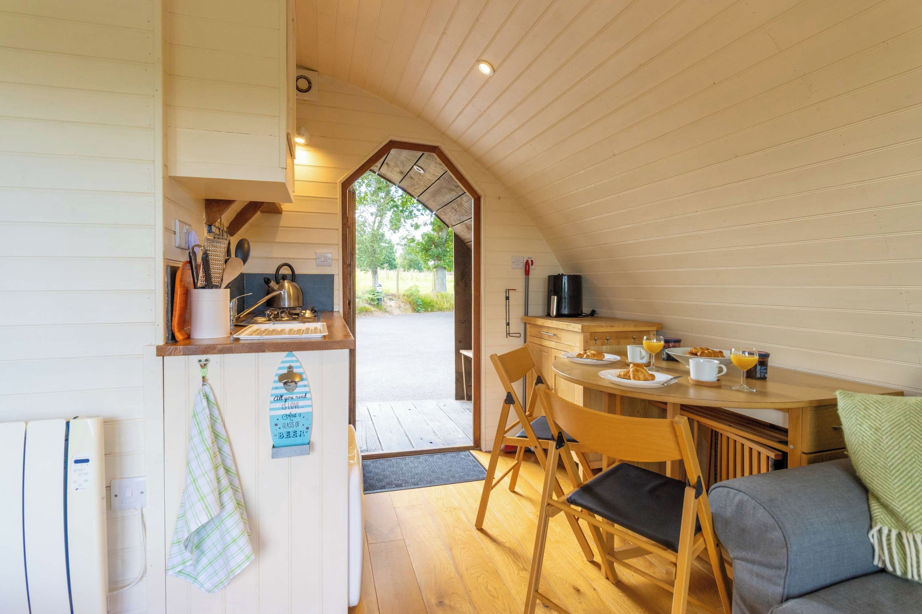 A cozy kitchen with wooden cabinets, a dining table set for two, and a view of the outdoors.