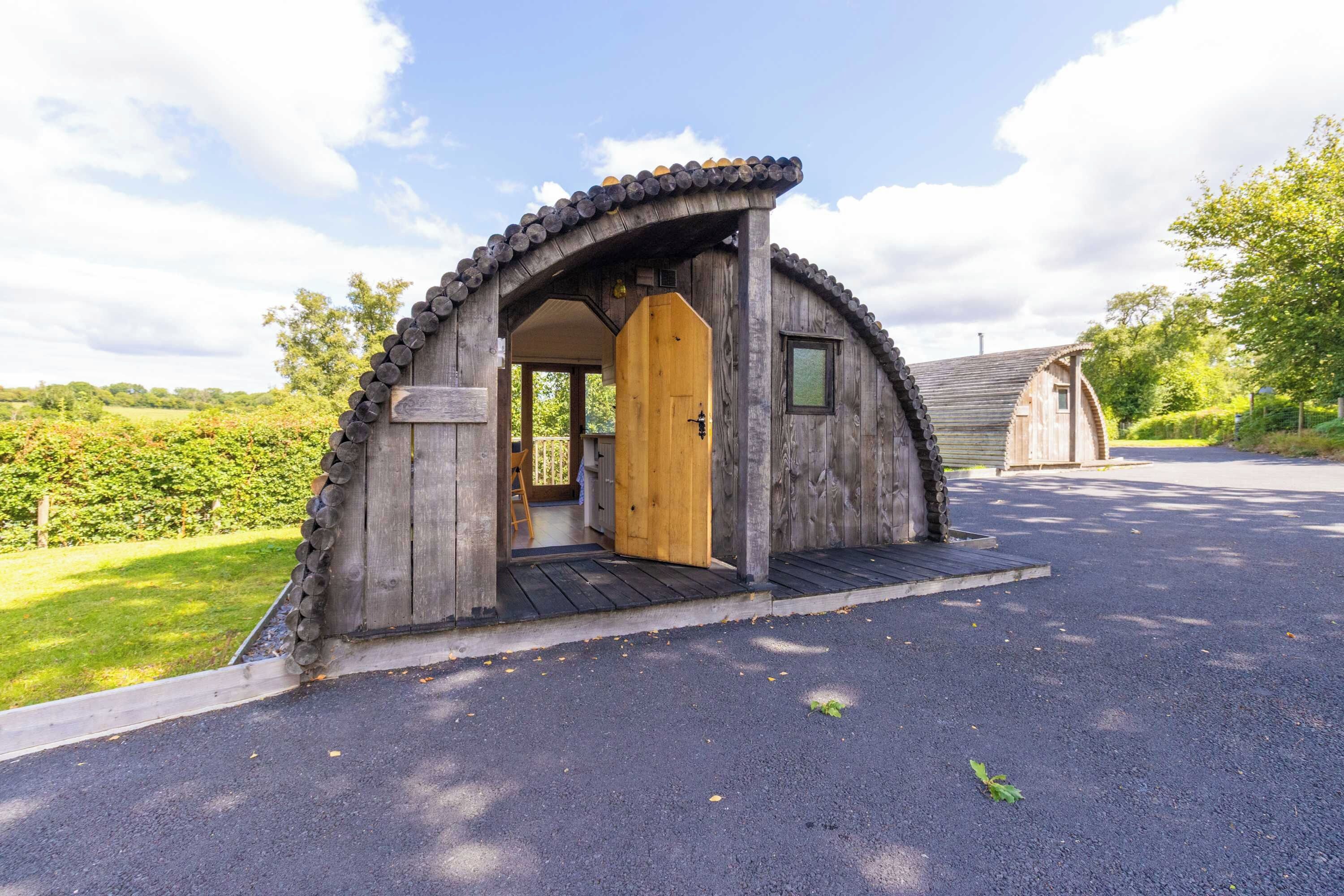 Une structure en bois dotée d’une porte, d’un petit porche et d’une zone pavée devant l’entrée.
