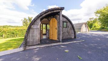 Une structure en bois dotée d’une porte, d’un petit porche et d’une zone pavée devant l’entrée.