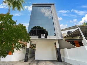 A modern hotel with a reflective glass facade, a sign indicating it's a 5-star serviced hotel, and a clear sky. - Premium Pullans Arcade (Kanayannur)