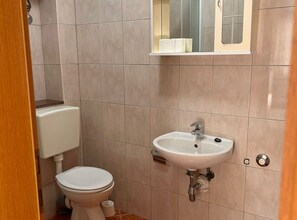 Ein Badezimmer mit Toilette, Waschbecken und Spiegel.