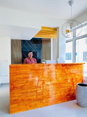 A reception desk with a modern design, a large window, and a hanging light fixture. - YUVi blue maldives (Himmafushi)