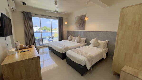 A hotel room with two beds, a desk with a computer, a TV, and a view of the outdoors.