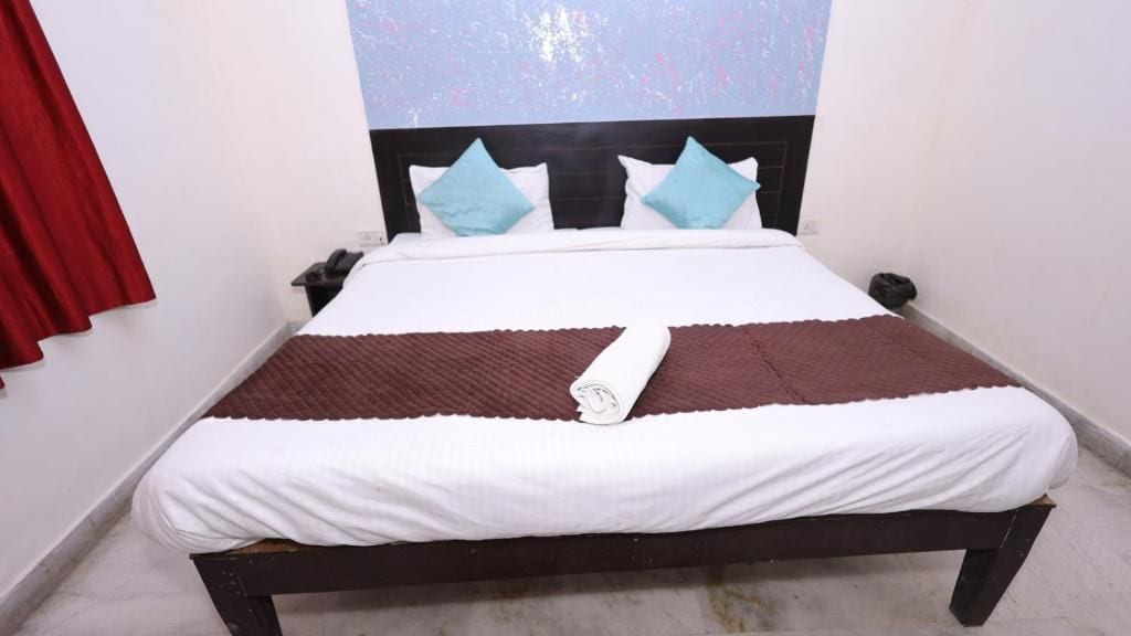 Una cama con un edredón blanco y marrón, un cabecero negro y dos almohadas azules.