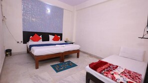 A bedroom with two beds, a blue mat, and a red and white patterned blanket. - Hotel NoVo Agra (Agra)