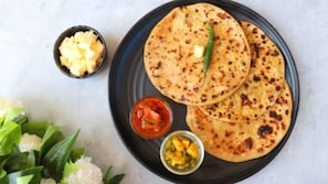 A plate with flatbreads, a bowl of chutney, and a small bowl of diced fruit. - Hotel NoVo Agra (Agra)