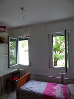 Une chambre à coucher avec un lit, un bureau et deux fenêtres.