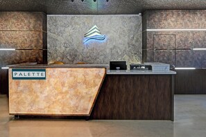 A reception desk with a marble top labeled 'PALETTE,' a logo above it, and a wooden panel to the right.
