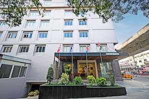 A multi-story hotel with a modern facade, multiple flags, and a visible entrance. - Palette Madhapur (Hyderabad)