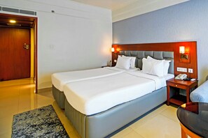 A double bed with a headboard, bedside tables with lamps, a telephone, and a small table with a lamp. - Palette Madhapur (Hyderabad)