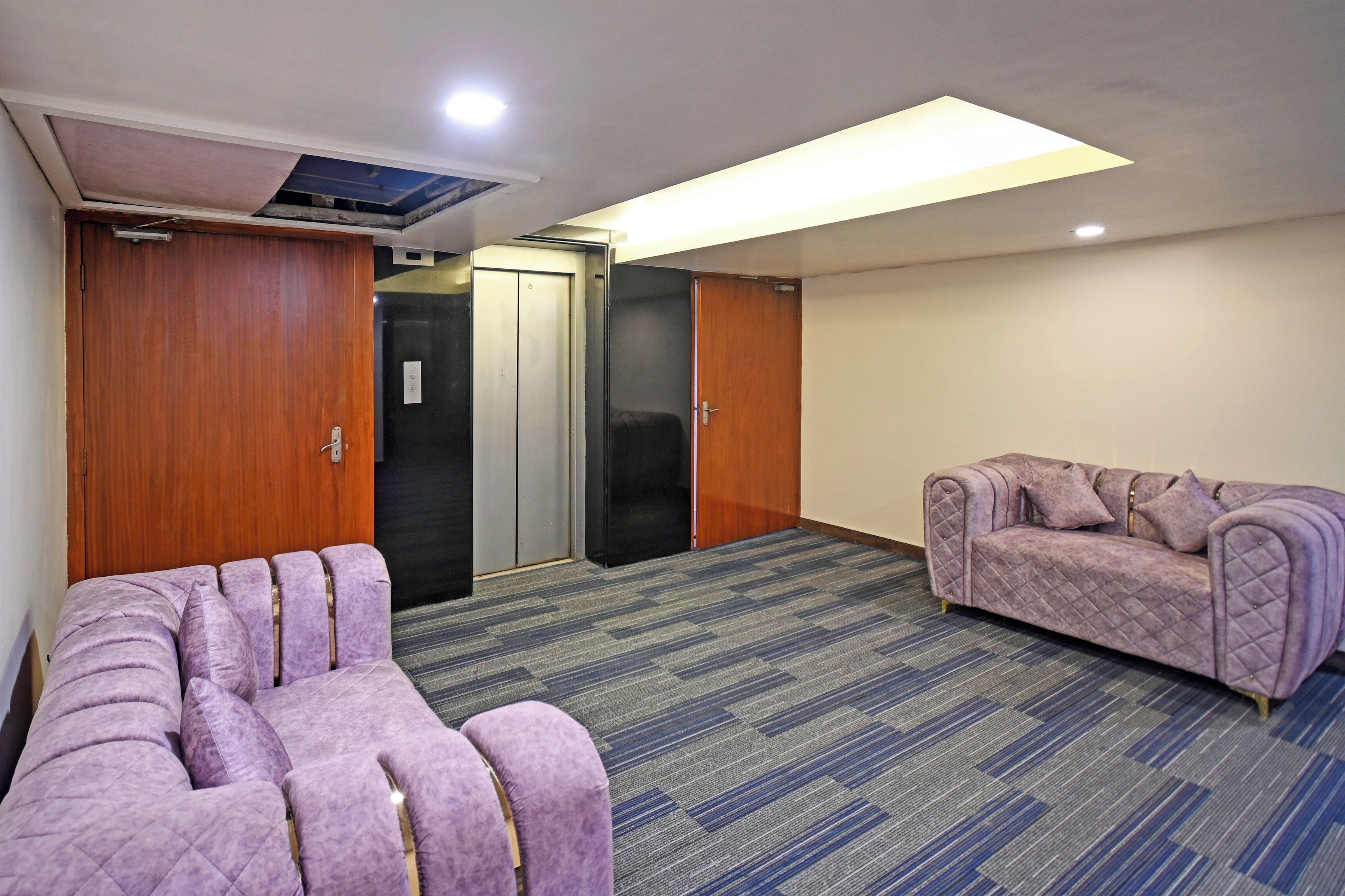 Habitación de hotel con una cama grande, un sofá, una silla de masaje y un mini bar.