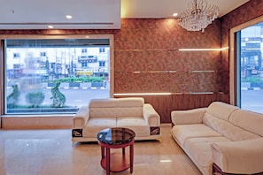 A modern hotel lobby with a large window, two sofas, a glass coffee table, and a chandelier. - Palette Madhapur (Hyderabad)