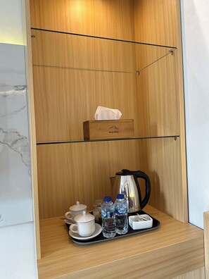 A wooden cabinet with a tissue box, a kettle, cups, and water bottles. - Monte Batur (Bangli)