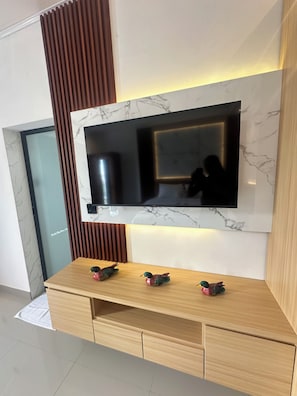Un soggiorno moderno con una TV a schermo piatto montata su una parete in marmo, pannelli in legno e un tavolino consolle in legno con decorazioni a forma di anatra.