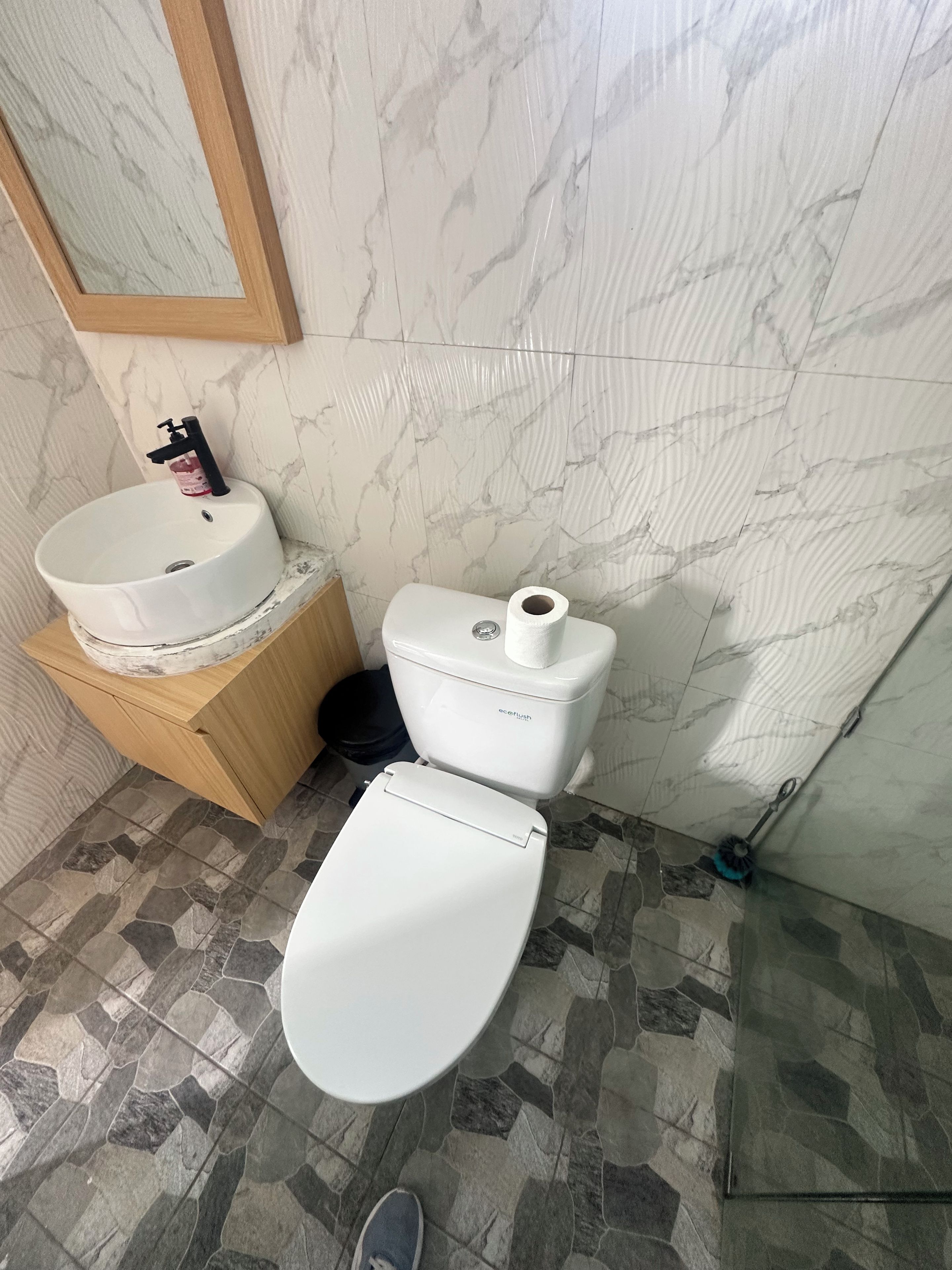 A bathroom with a white toilet, a sink, and a mirror.