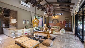 A spacious living area with a high ceiling, a fireplace, and a large window providing a view of the outdoors.