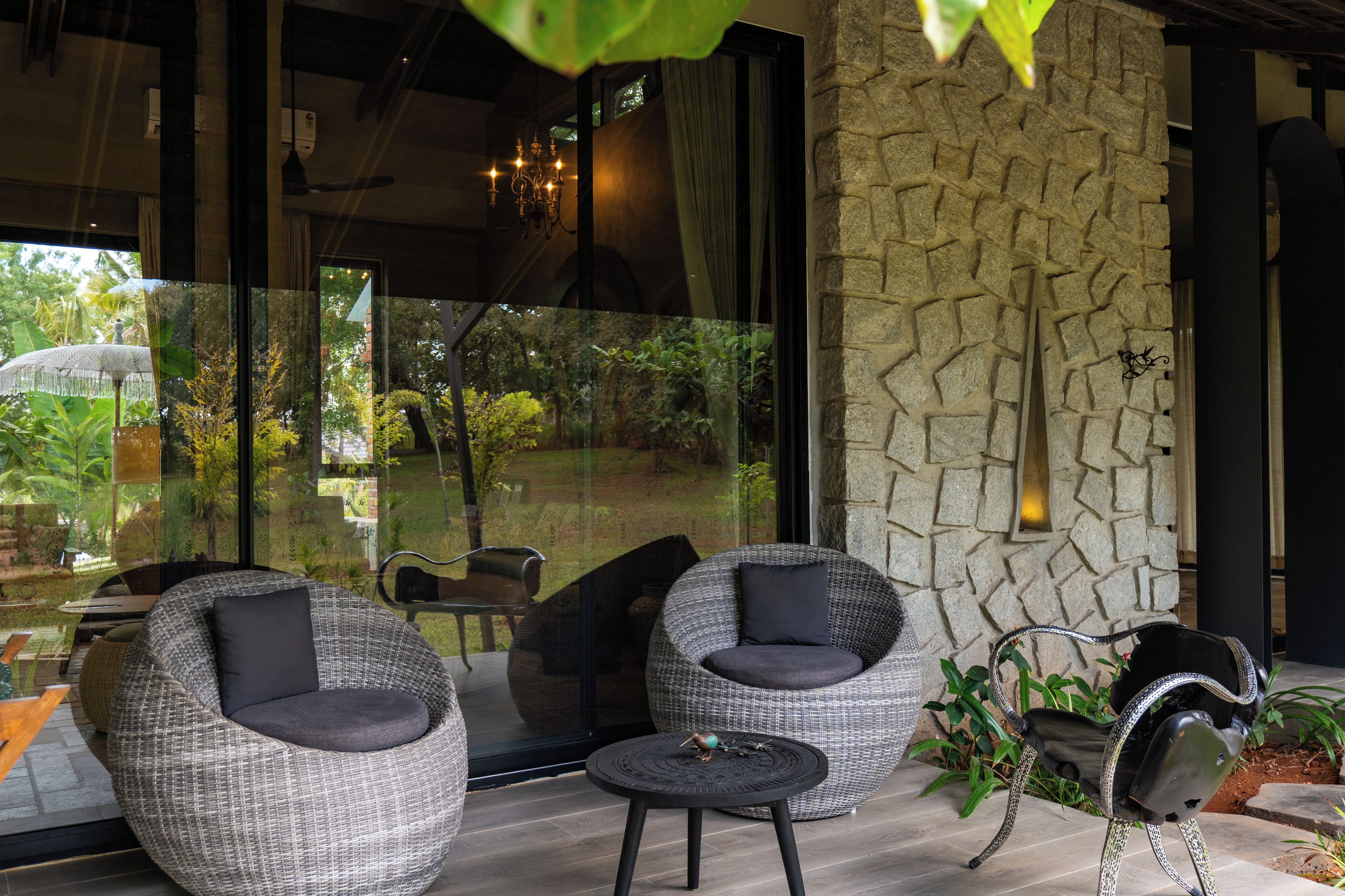 A modern outdoor seating area with wicker furniture and a stone wall.